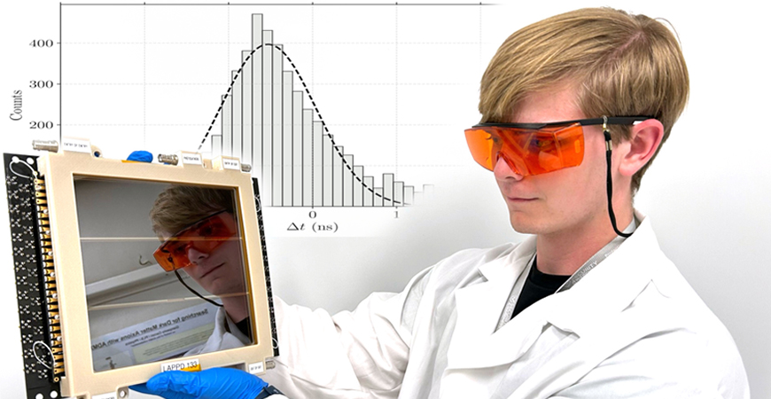 male grad student wearing white lab coat and orange goggles in front of computer