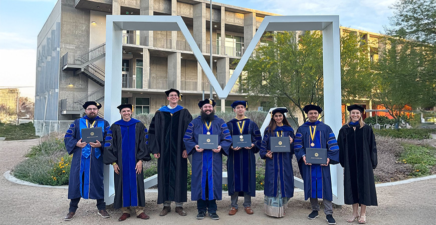 Physics faculty and graduate students pose in front of the M on campus